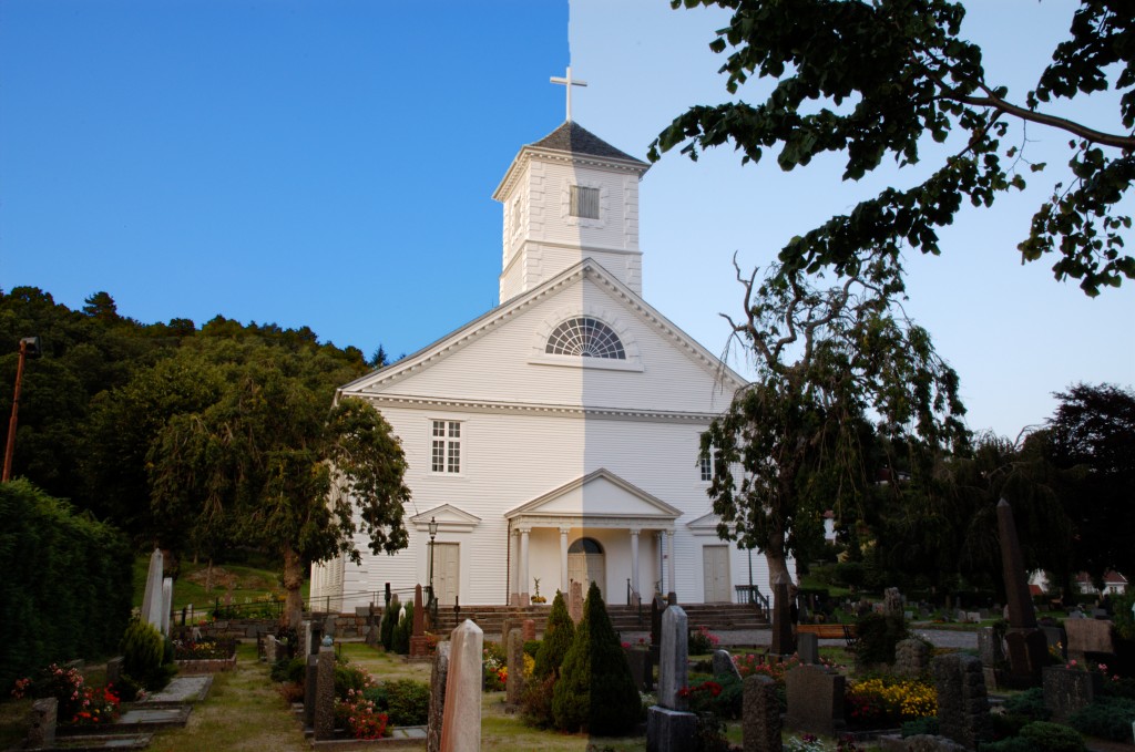 a white church and graveyard in an area with trees