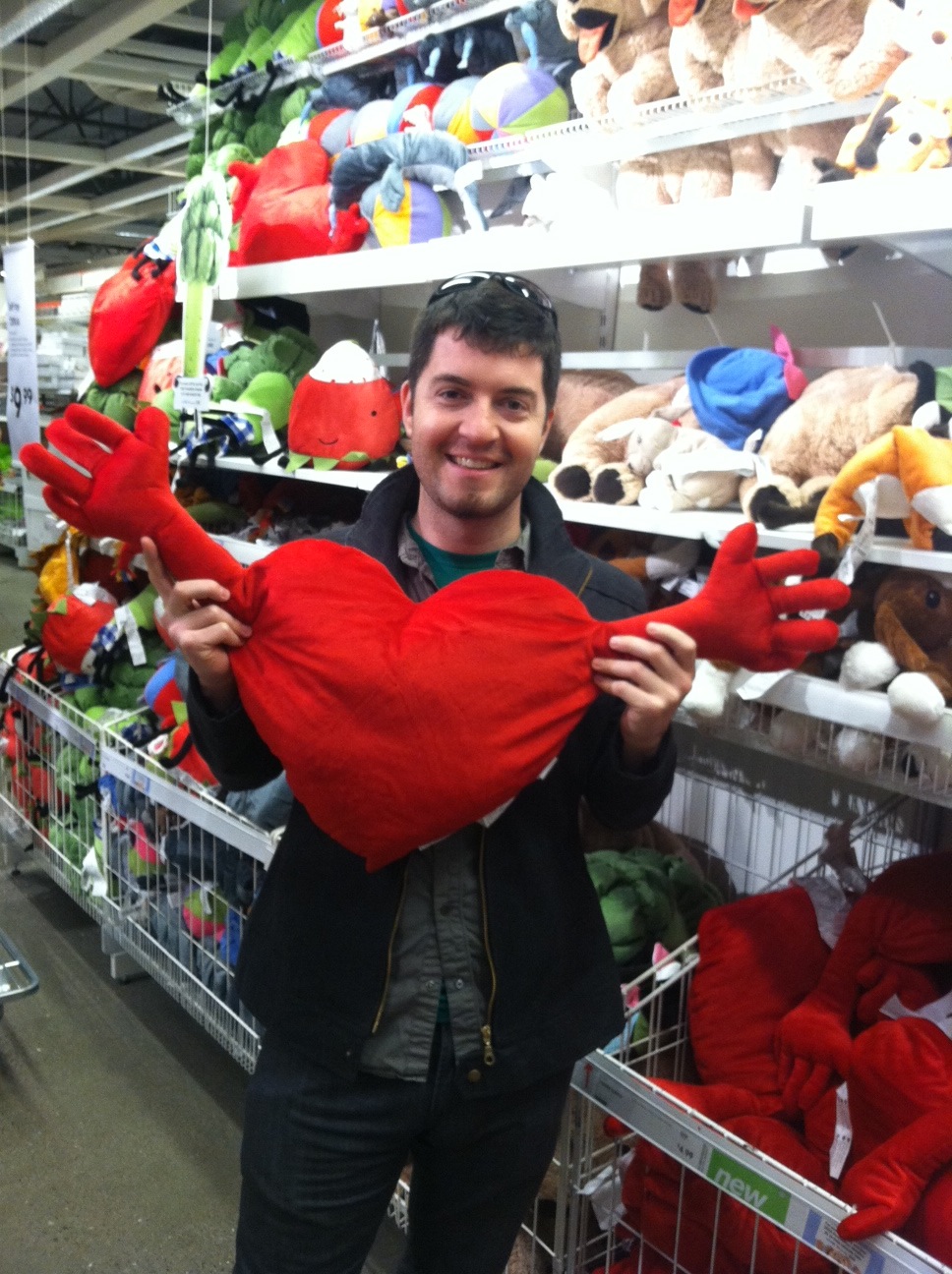 a man smiling holding up a stuffed heart