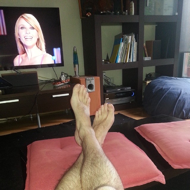a guy laying on a bed in front of a tv watching porn