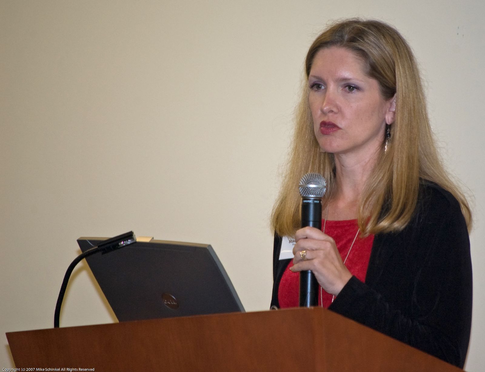 a woman standing at a podium while talking to someone