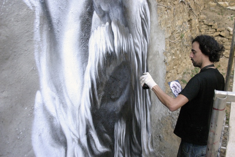 a man painting a mural on a concrete wall