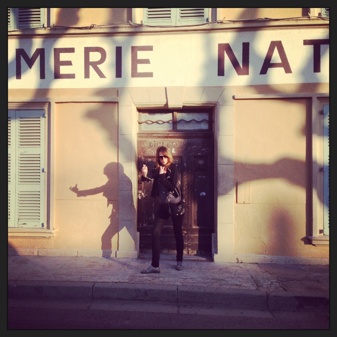 woman standing at the door of a building pointing at a shadow on the ground