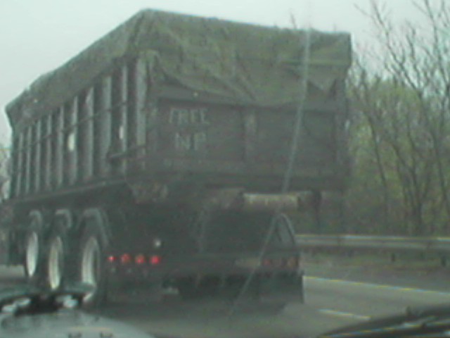 a truck carrying logs drives through a rain storm