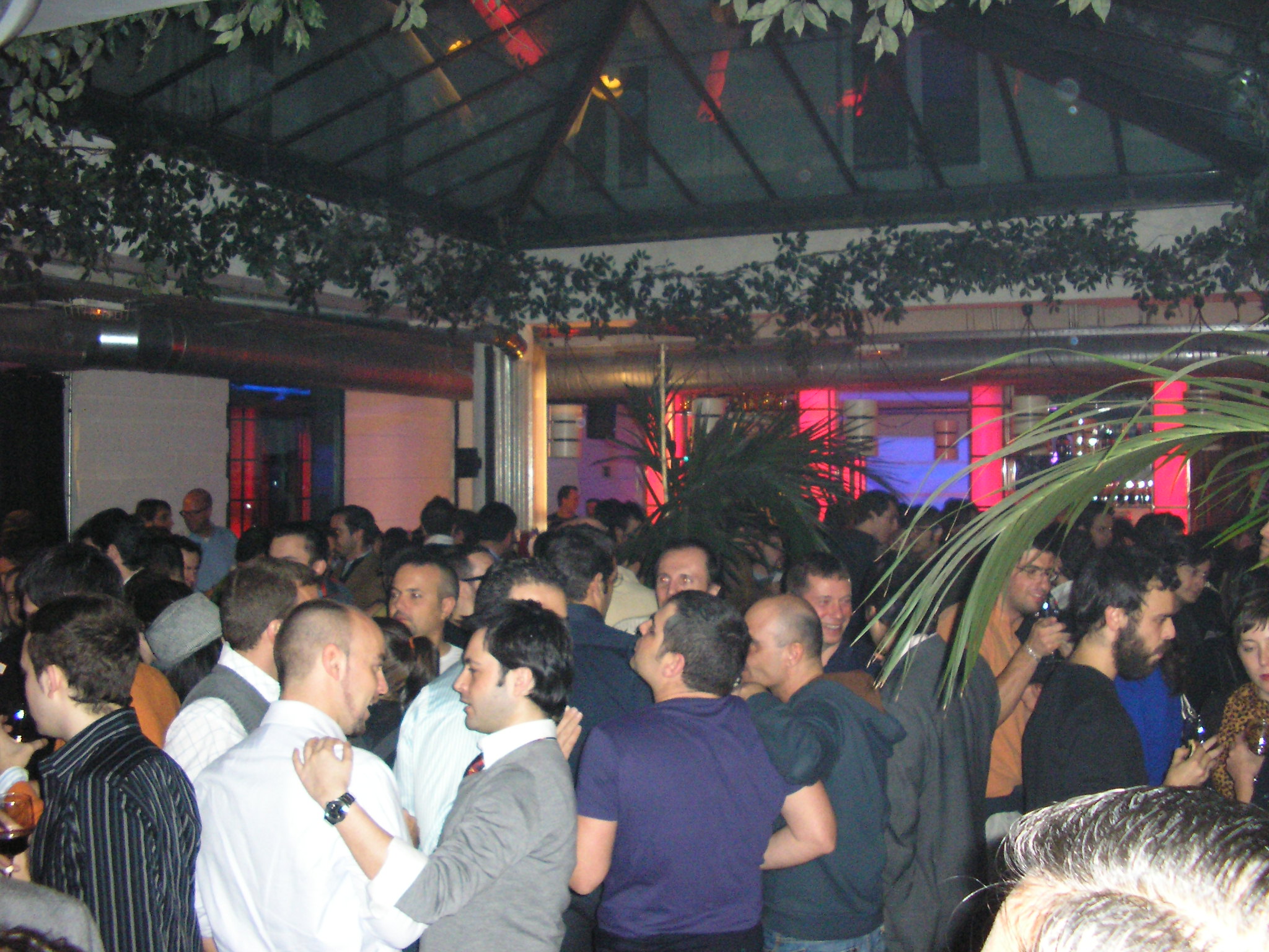 a crowded, crowded restaurant has some plants hanging from the ceiling