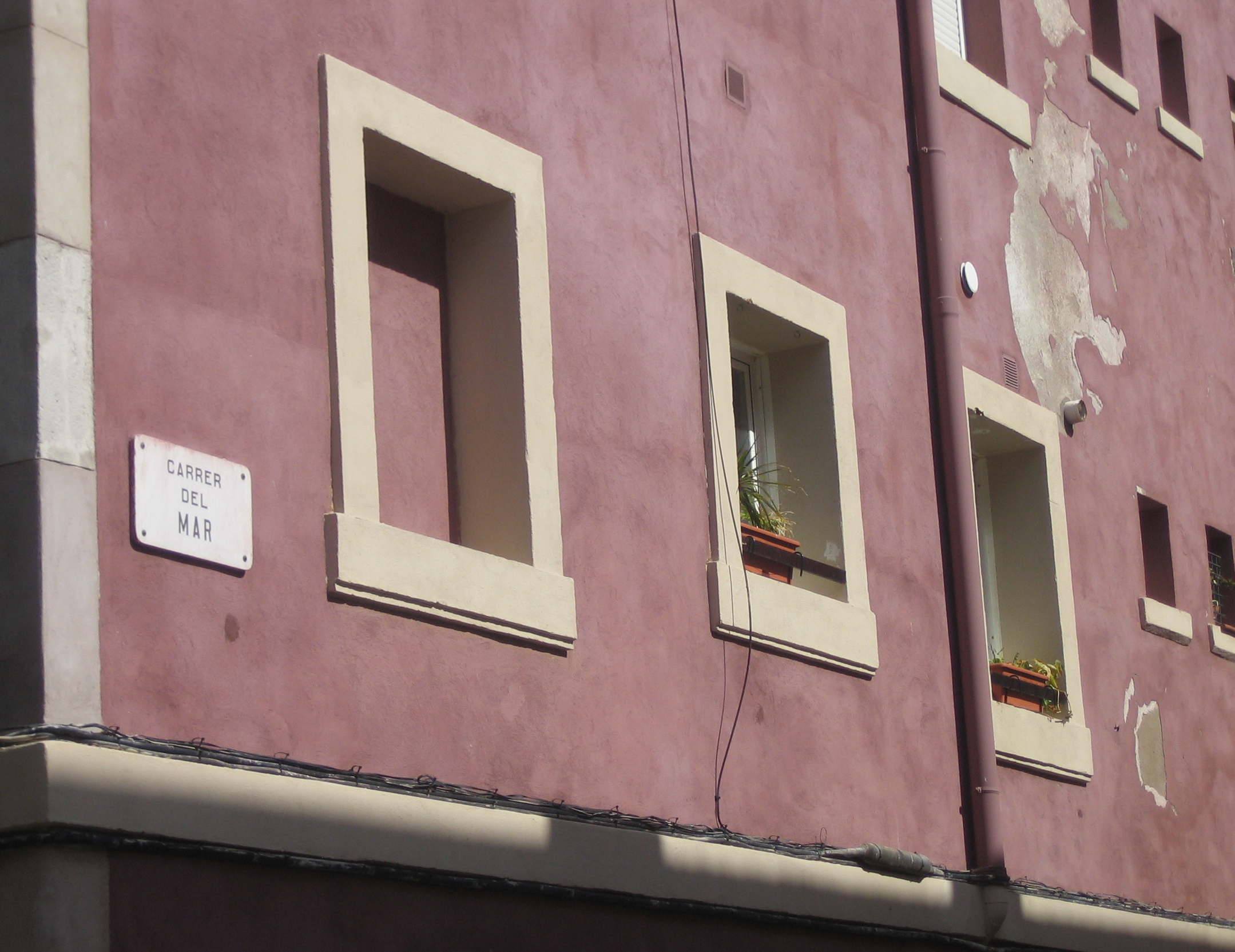 two windows sit near each other as a sign stands below