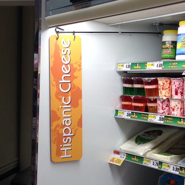 the hanging sign says happy cheese in front of some packaged dairy items