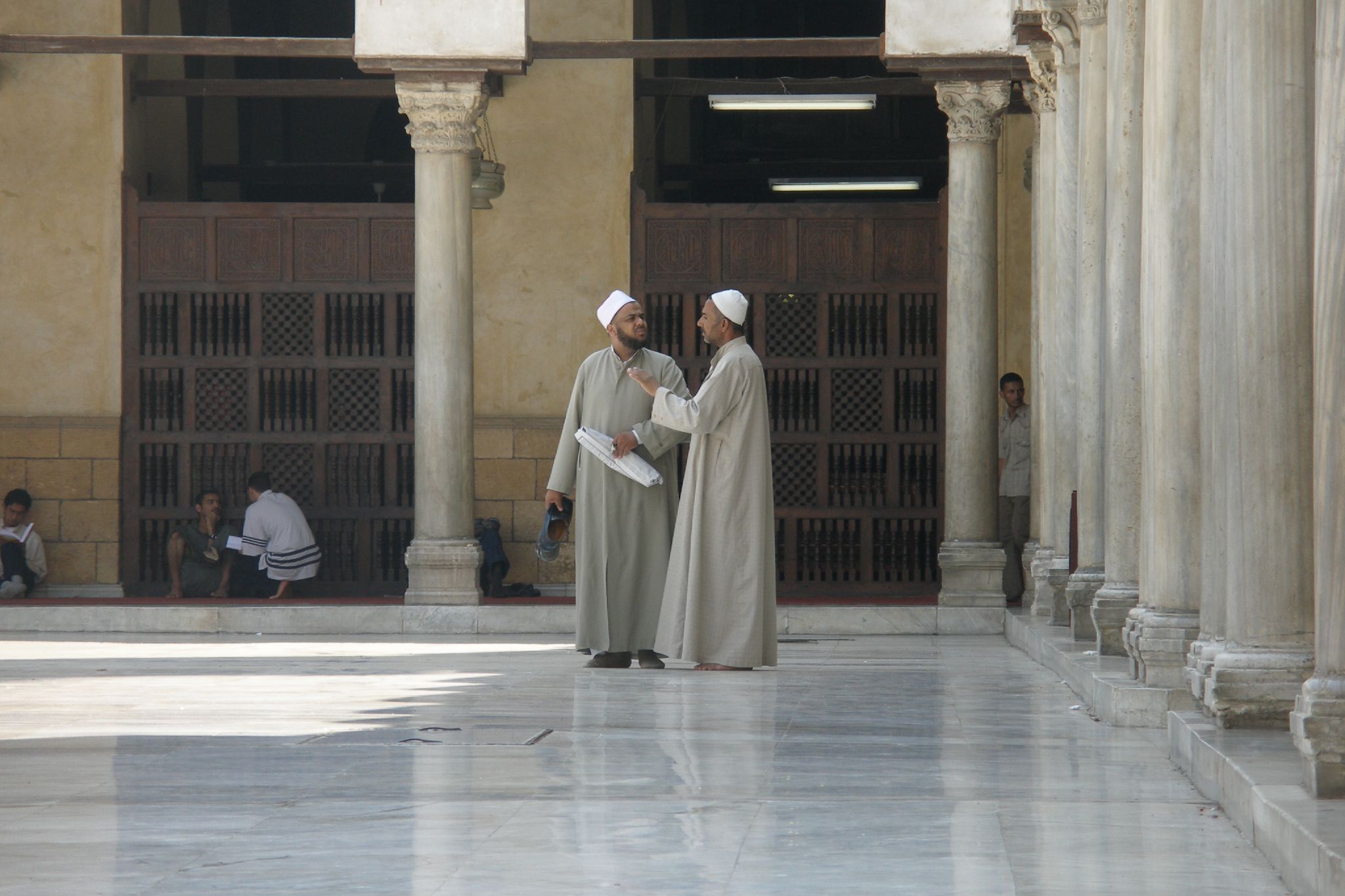 two women talking to each other in front of pillars