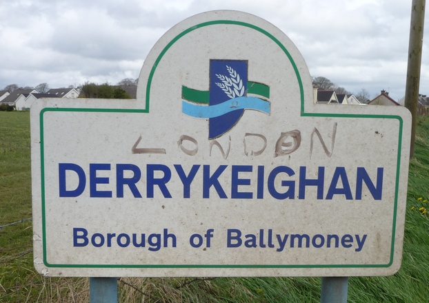 a large sign sitting in the middle of a green field