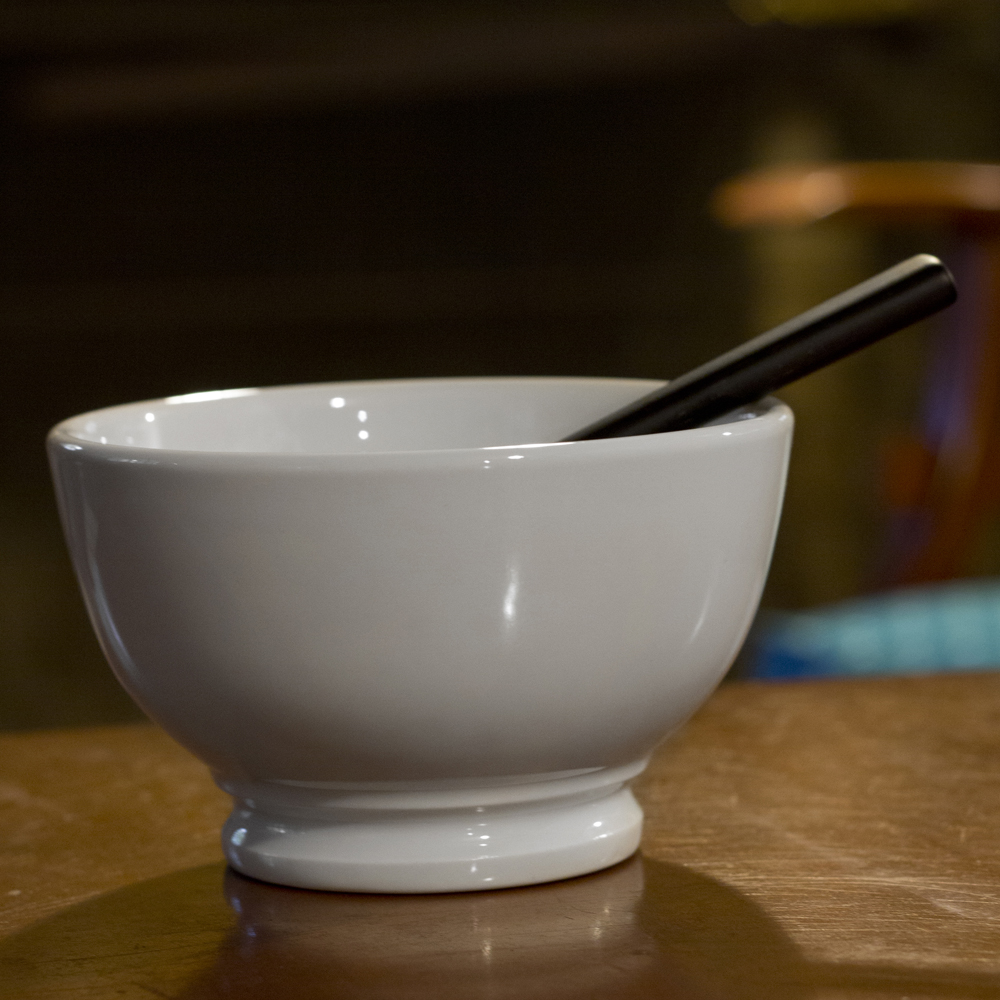 a bowl with two chopsticks inside sits on a table