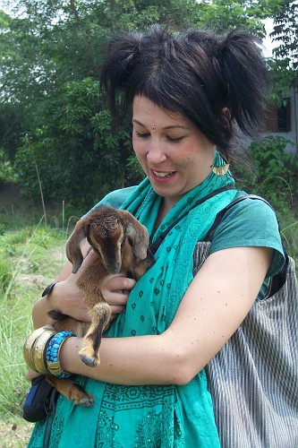 a woman holding a little baby goat in her arms
