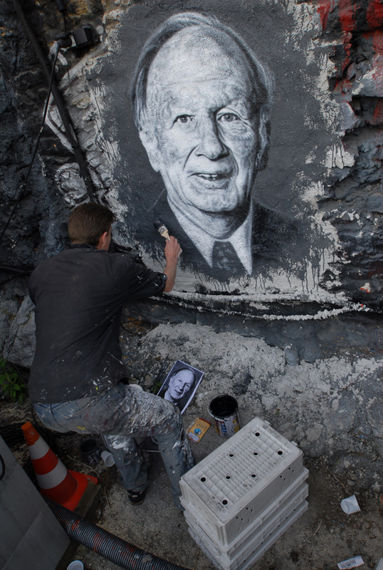a man is painting a large portrait on a wall