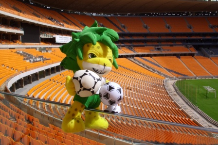 the stuffed animal is posed in front of the empty stadium