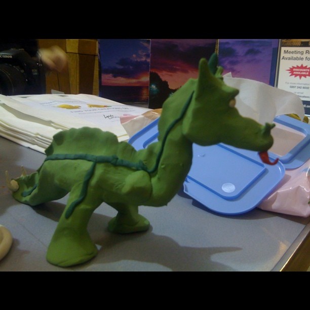 a toy dinosaur walking up to a blue tray