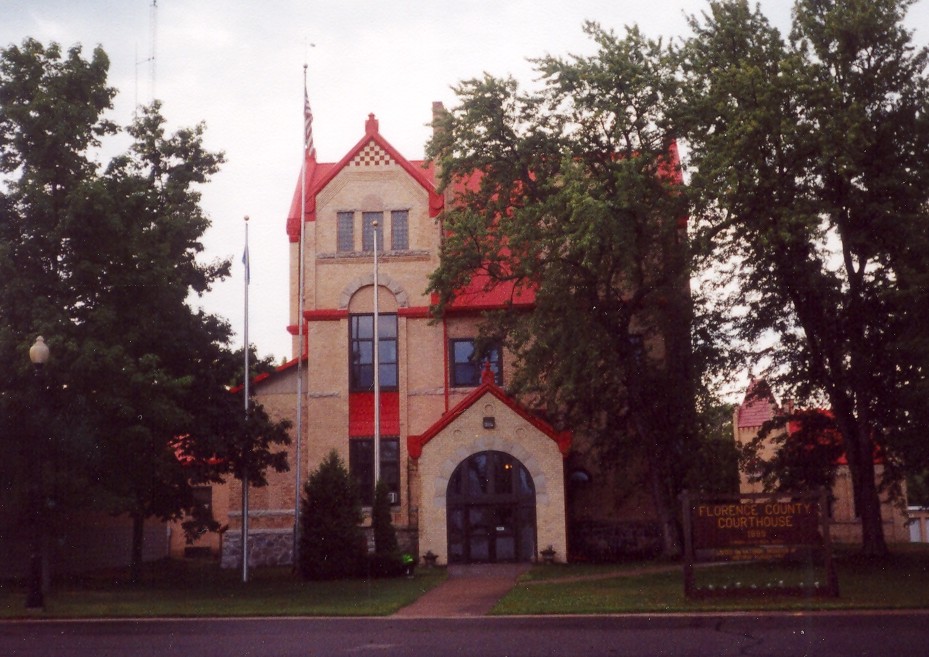 a large brown building with a red roof and many trees in front