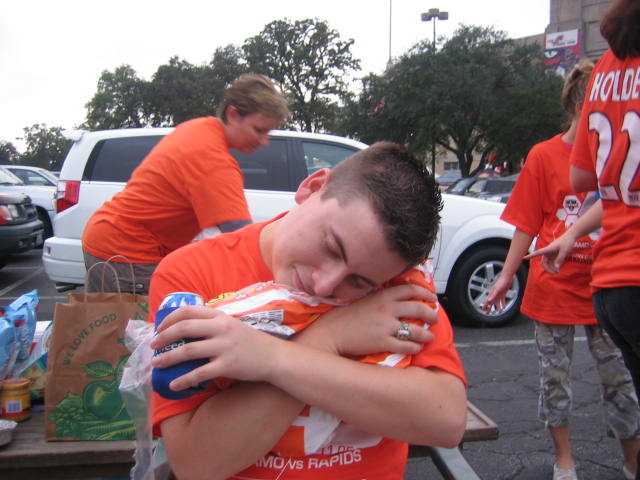 a man hugging his hand while people walking by are in the background