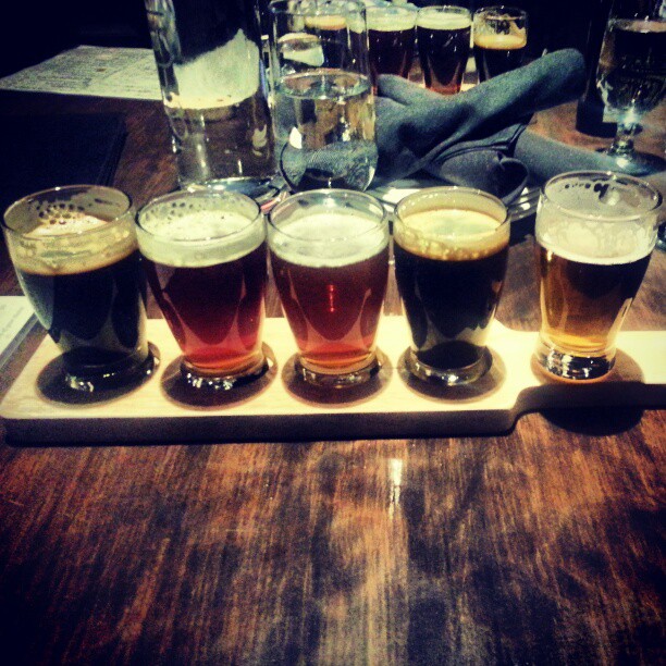 a table topped with five glasses filled with beer