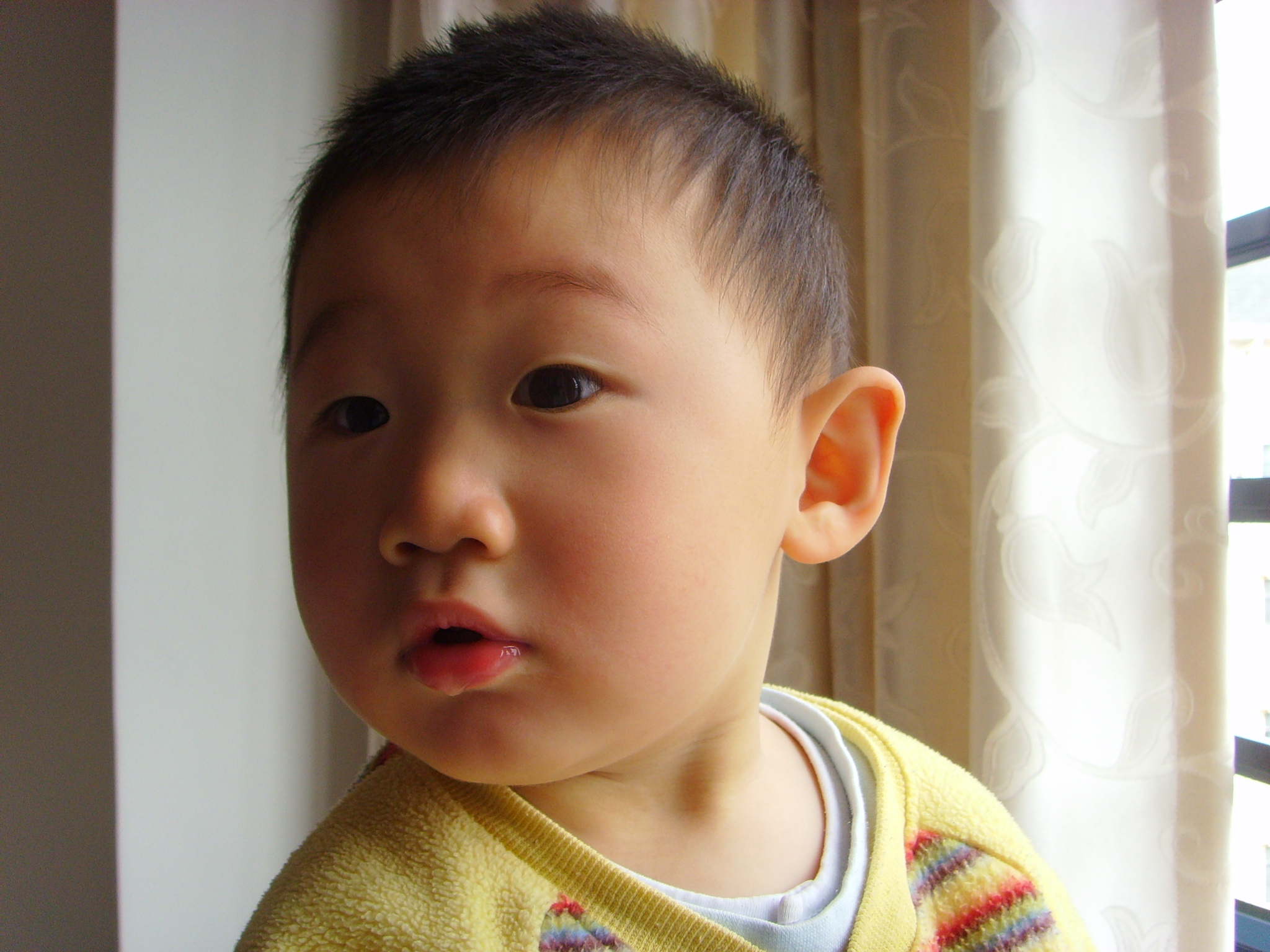 a young child wearing a yellow sweater is looking away from the camera