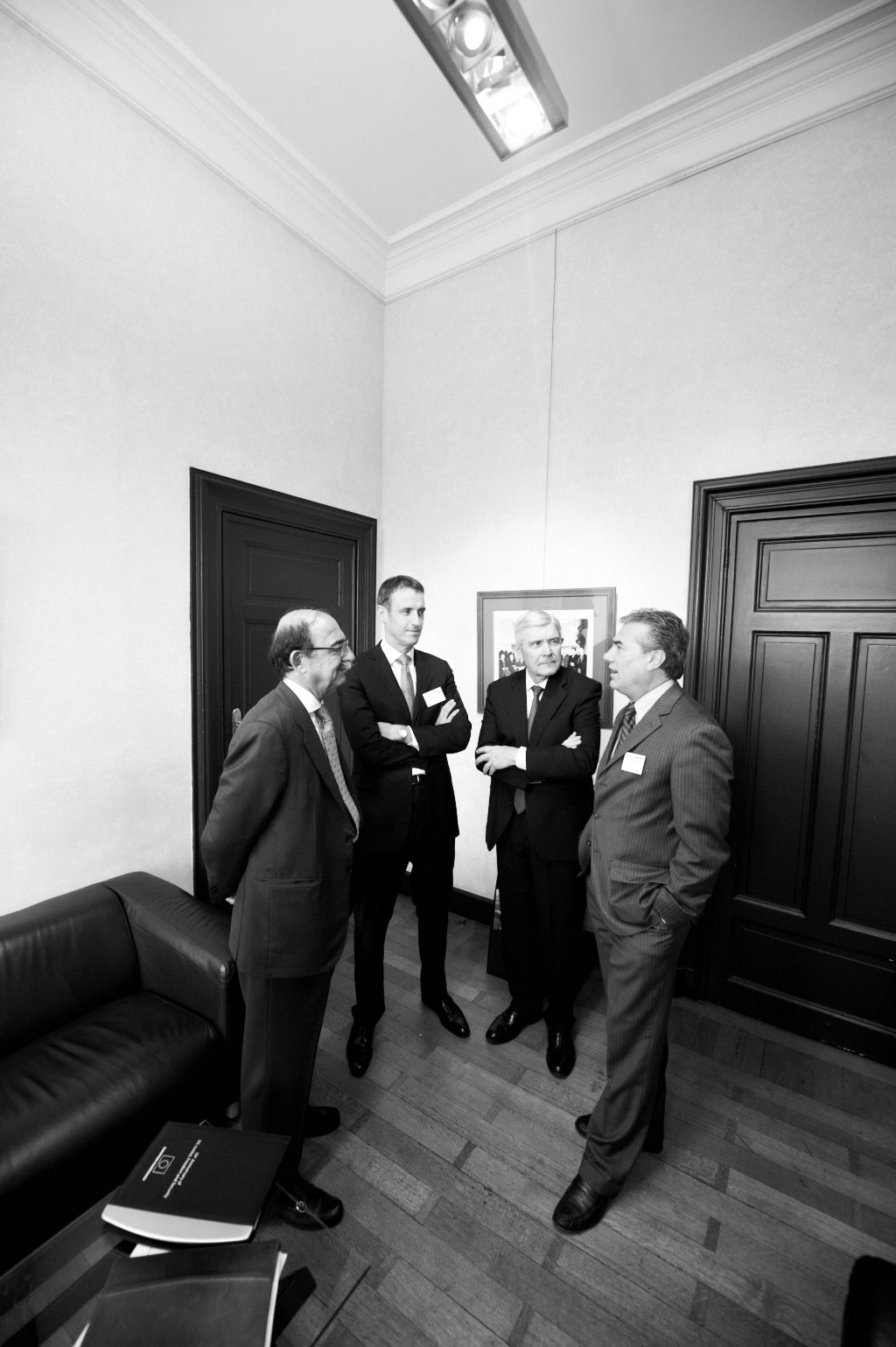 four men wearing business attire talking inside a large room