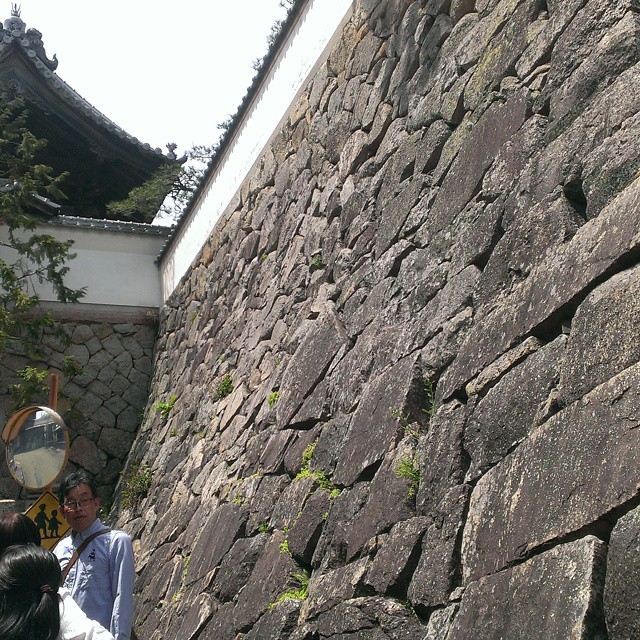 a tall stone wall and two men taking pictures