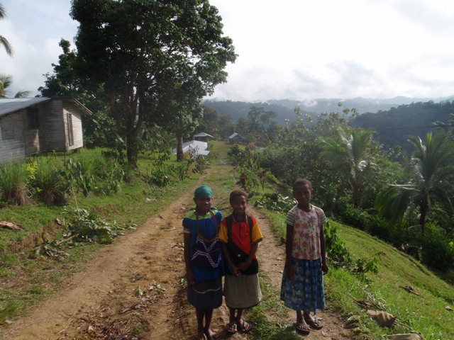 three women are walking on the side of the dirt road