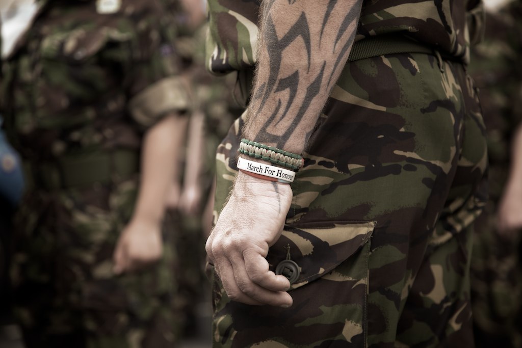 military holding their id badge in front of people