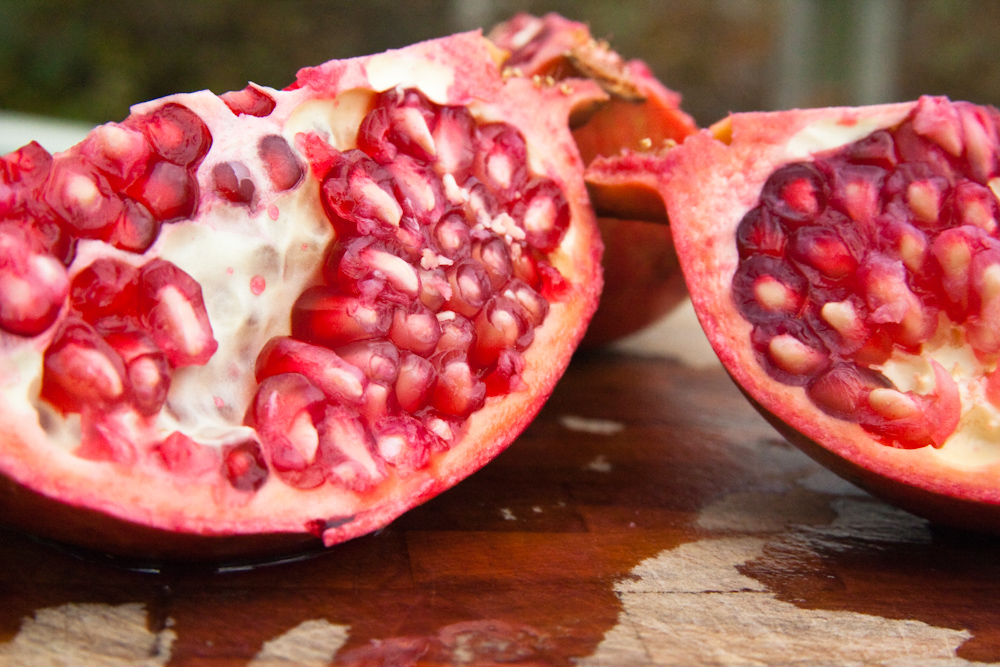 a cut in half pomegranate sits on a wooden surface