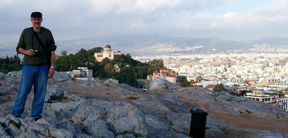 man standing on a rock overlooking a city