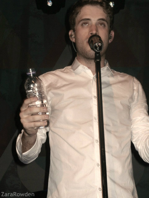 a man holding a microphone while standing up and singing