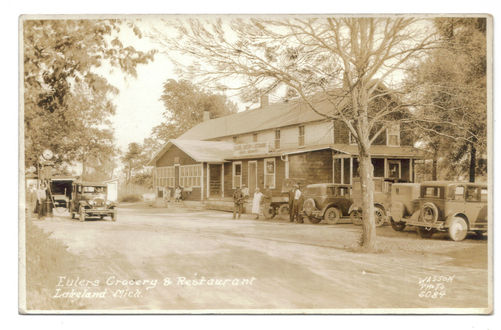 people stand outside of a vintage store and some vehicles