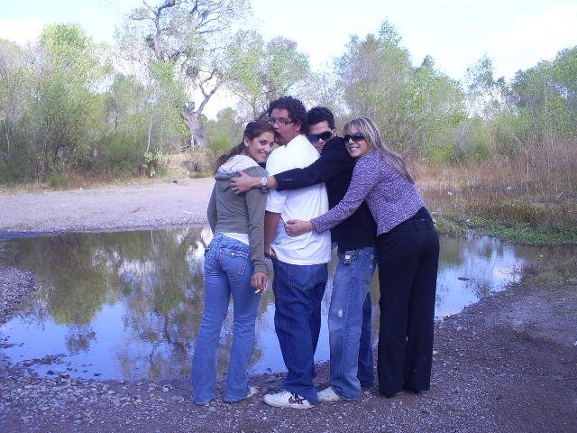 a group of young people hugging on the bank of a small pond
