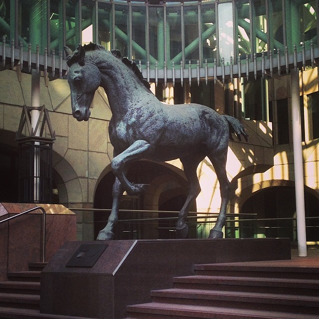 a statue of a horse running in front of stairs