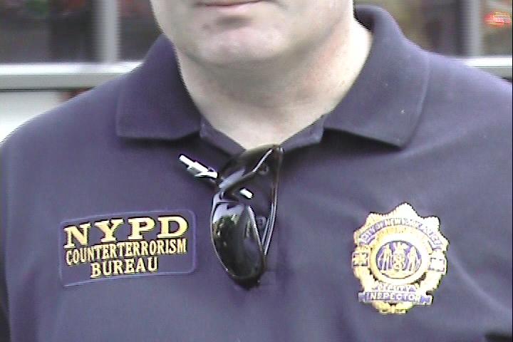 the man is wearing glasses and has nypd badge