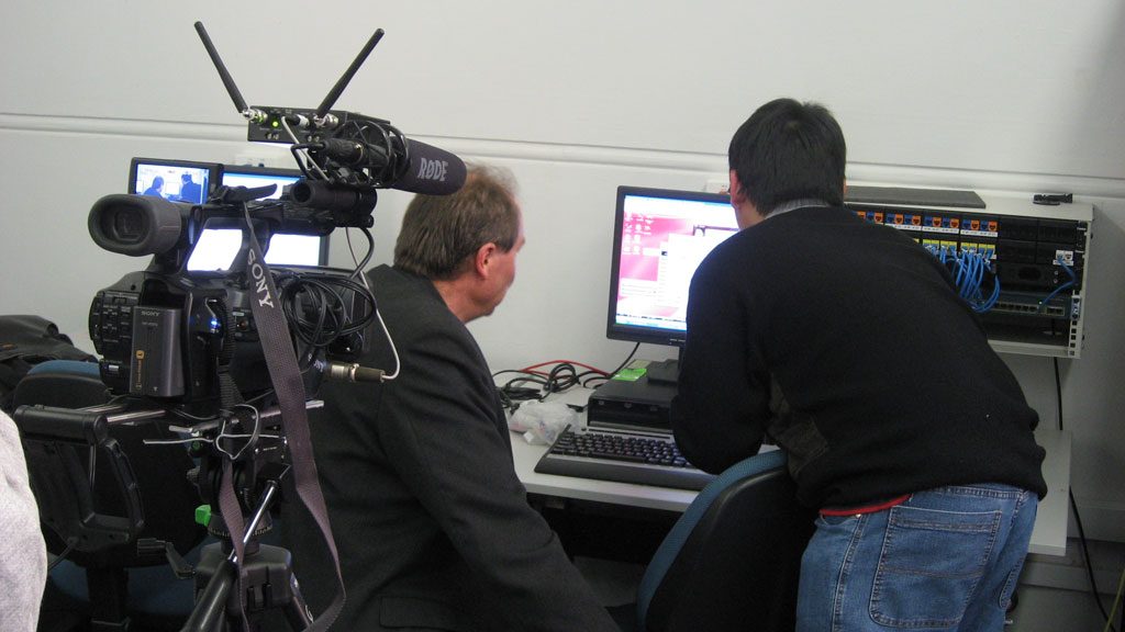 a cameraman operating multiple monitors while the man holds a camera