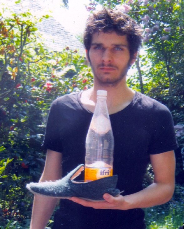 a man is holding an empty bottle and his shoe