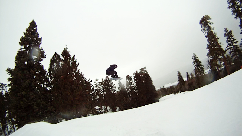 a person on a snowboard jumping into the air over some trees