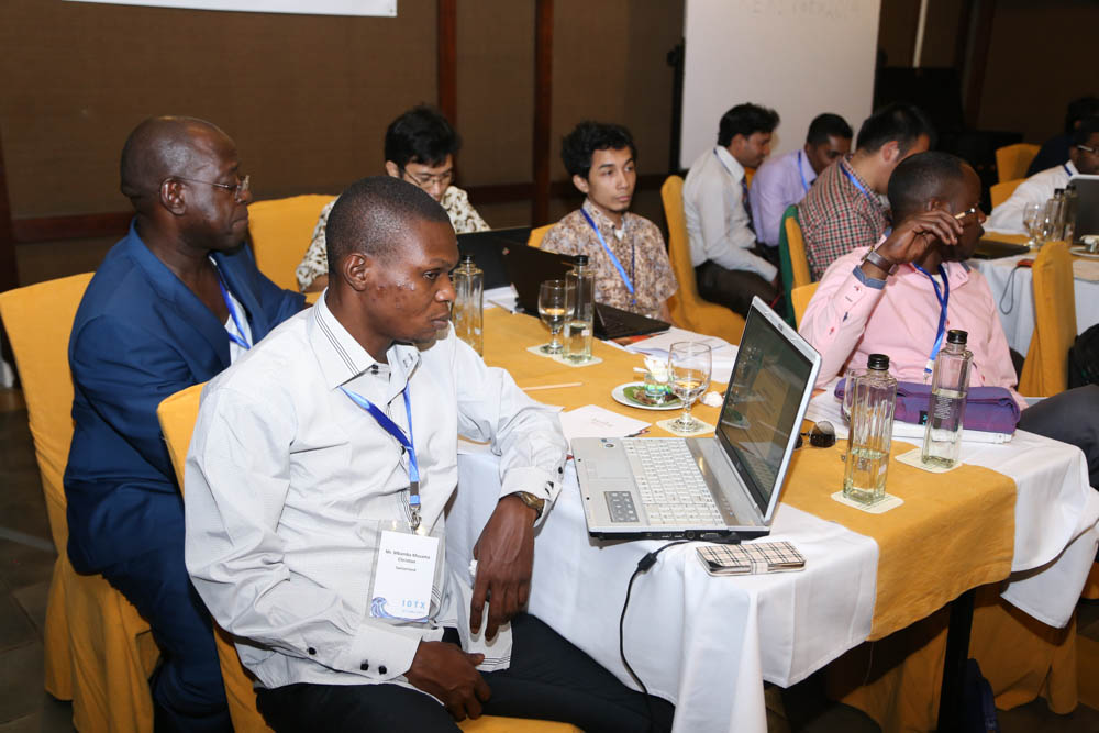 many people are sitting around a table with laptops