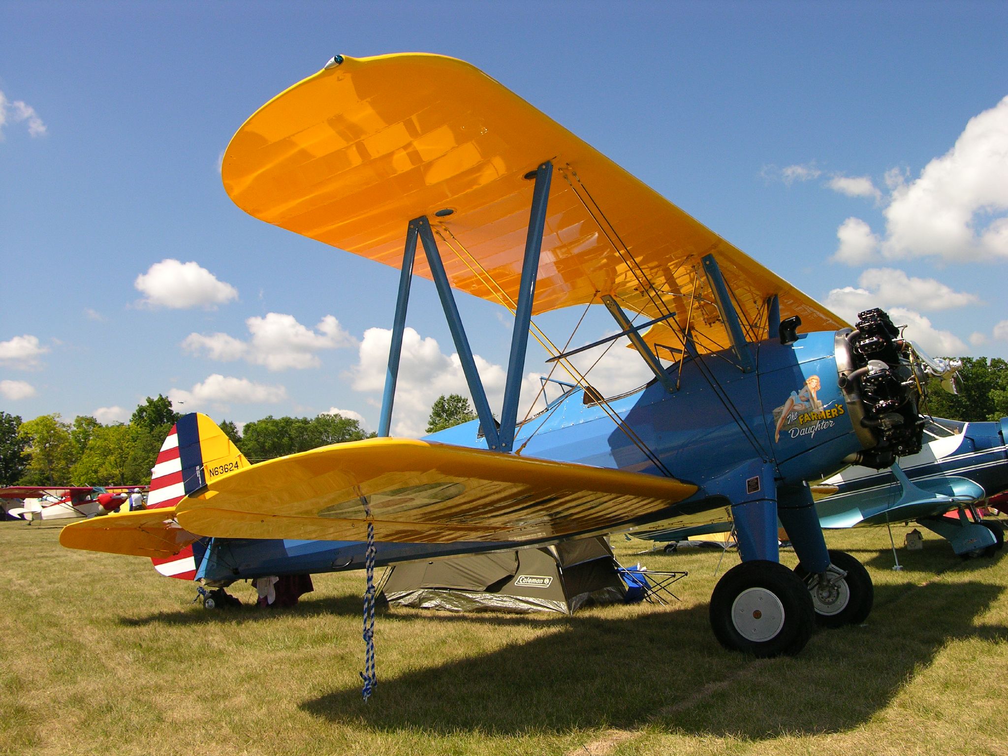 two vintage airplanes are parked in the field