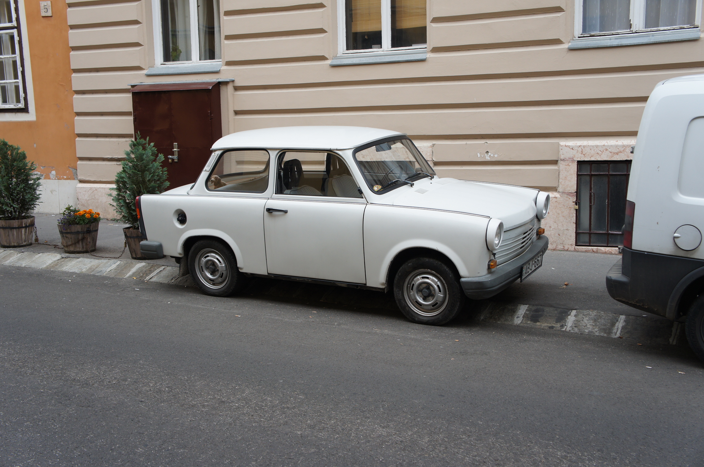 a white car parked next to a wall of brown buildings