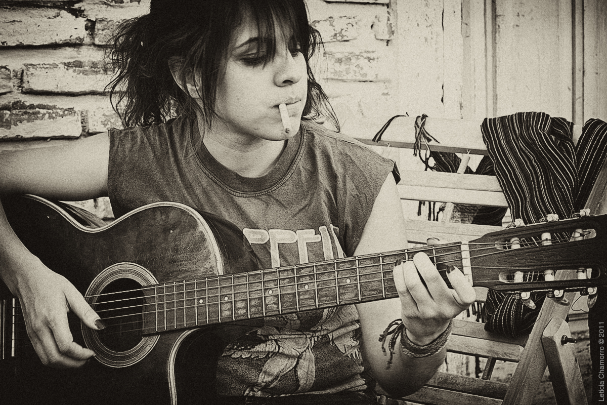 a girl sitting on a wooden bench with a guitar