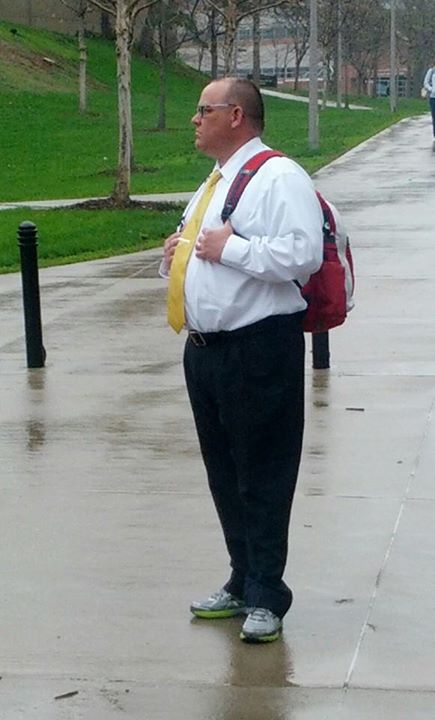 man wearing yellow necktie and suspenders walking down a sidewalk