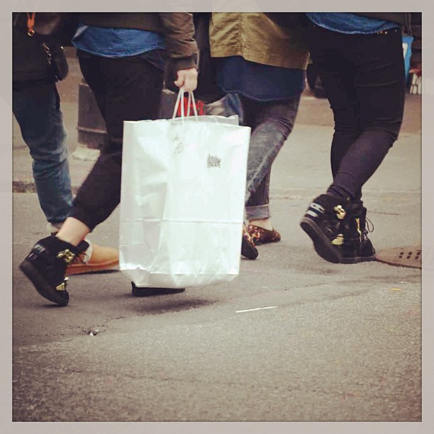 the bottom view of a group of people walking down the street with shopping bags on their feet