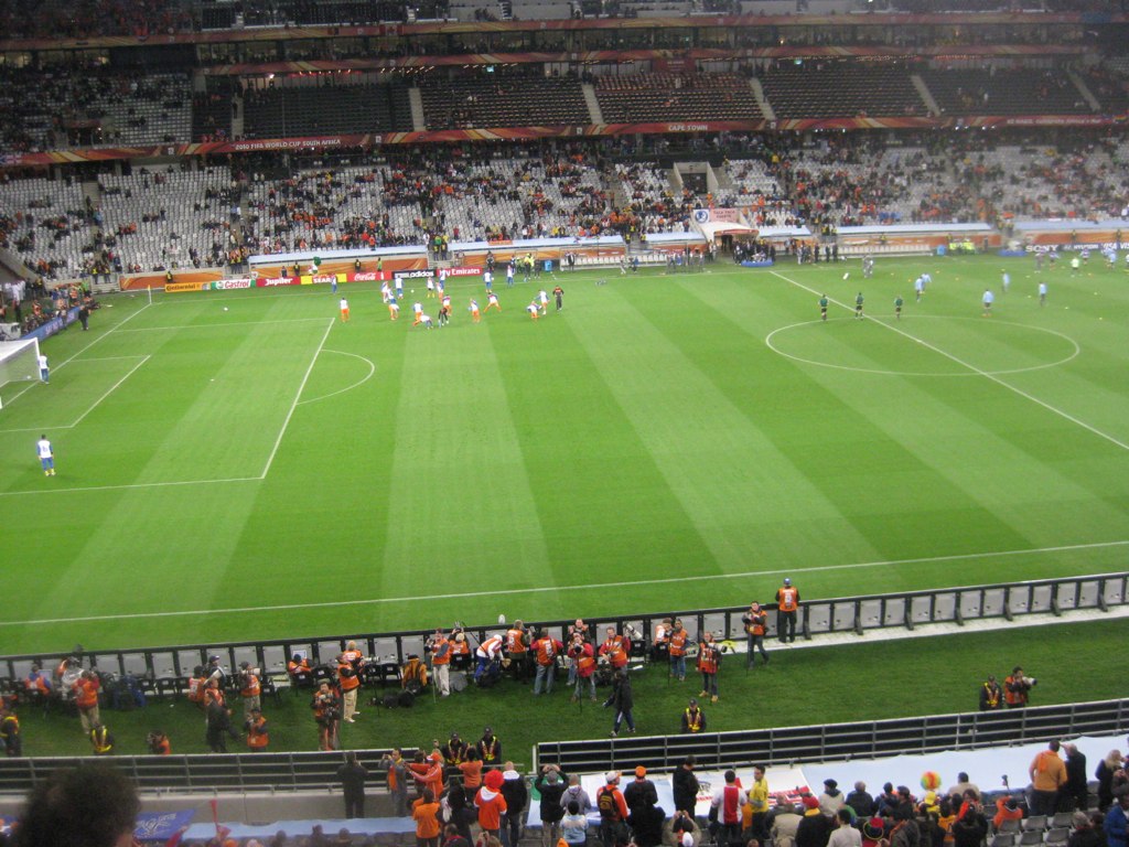 a stadium filled with people and a green soccer field