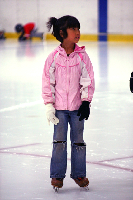 a little girl is standing on the ice
