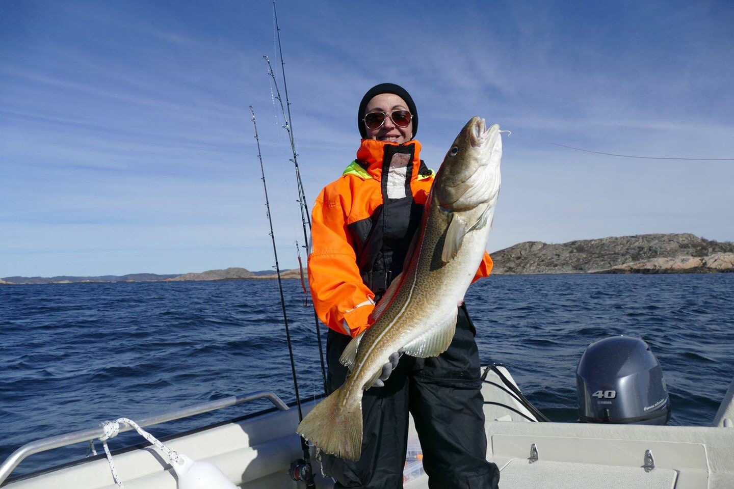 a man in orange is holding up a large fish