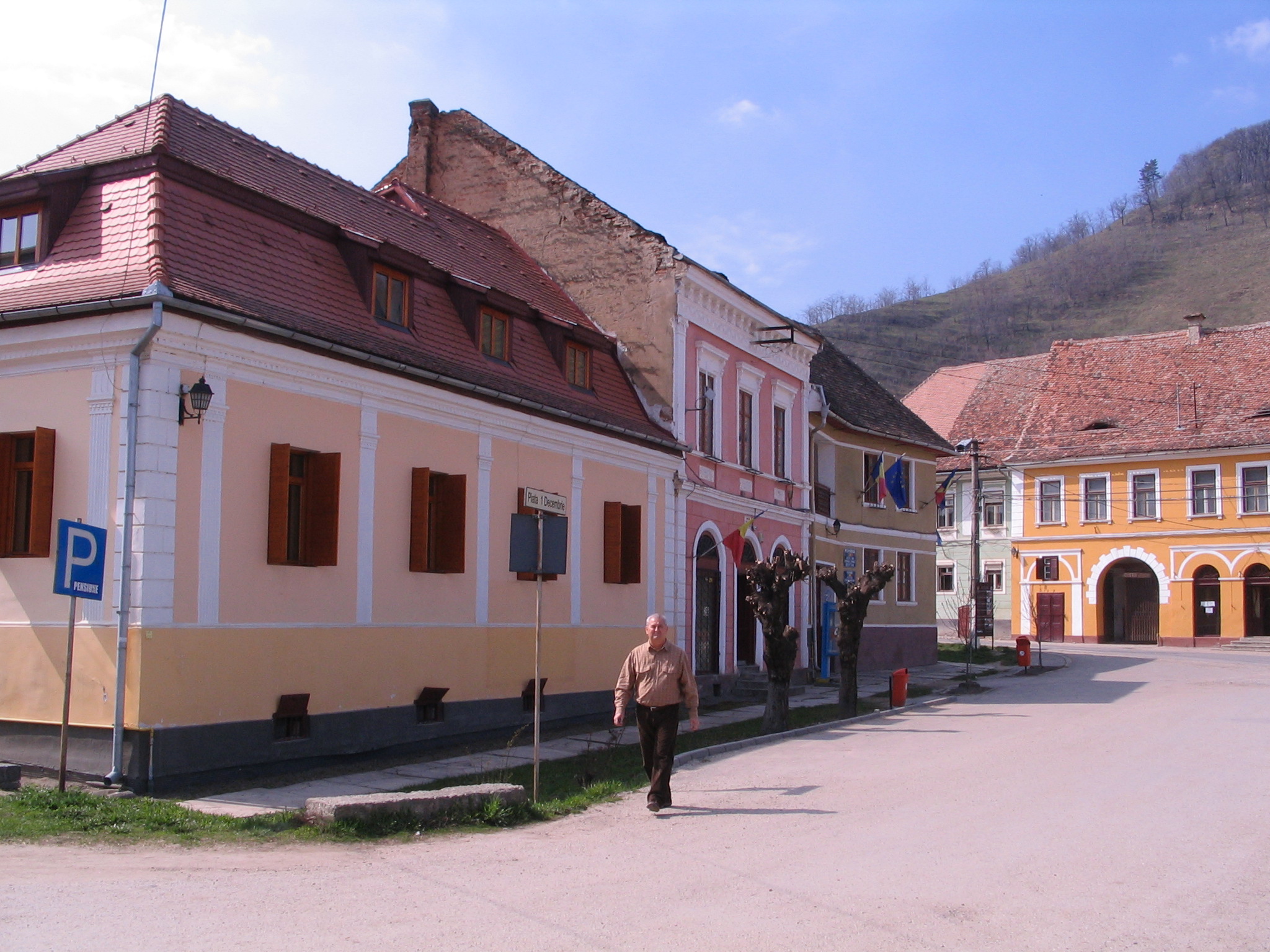 old people are walking along a large street in front of large buildings