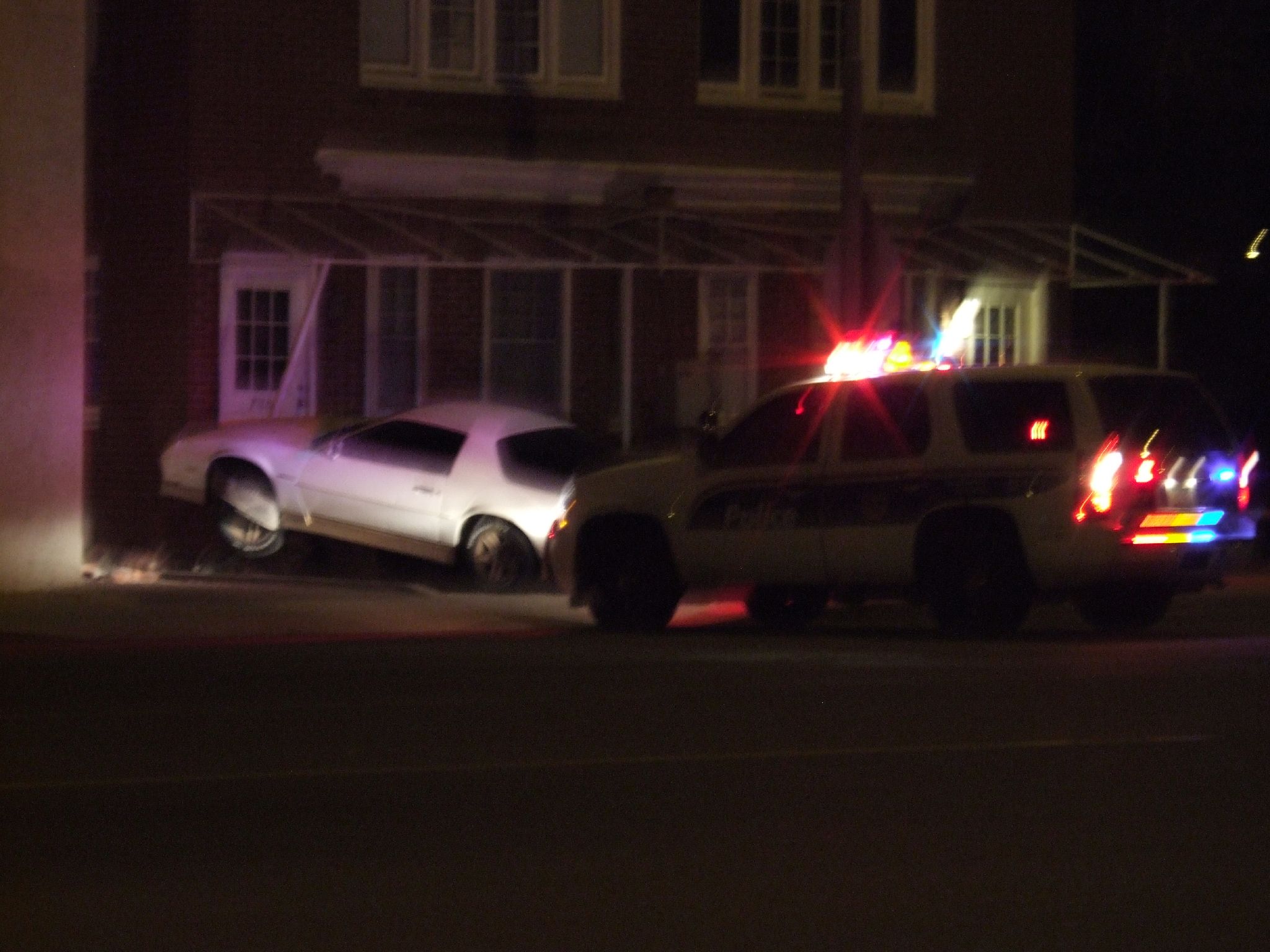 a couple of suv parked on the side of a road at night