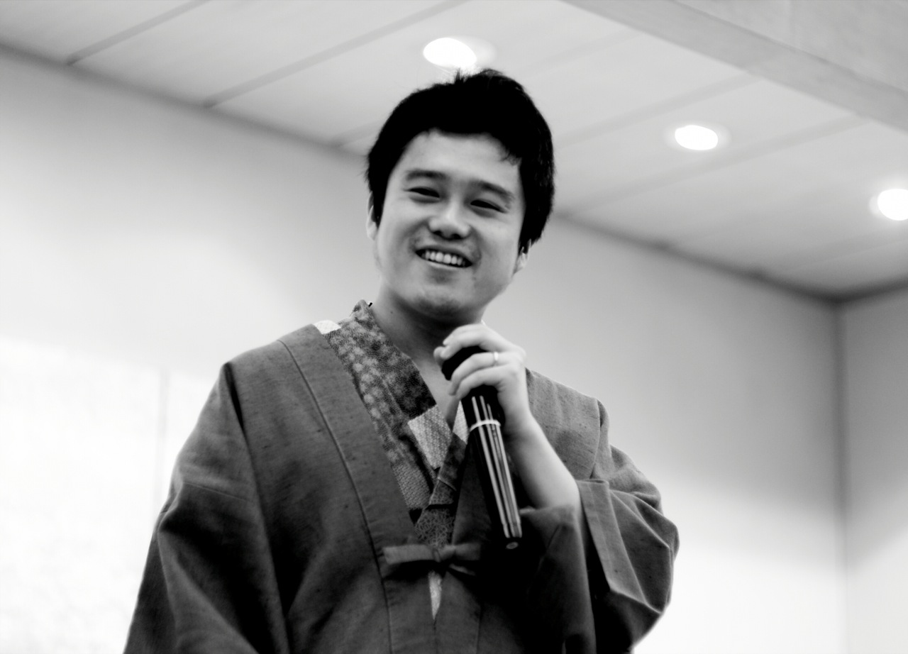 a man wearing a kimono smiling while holding an umbrella