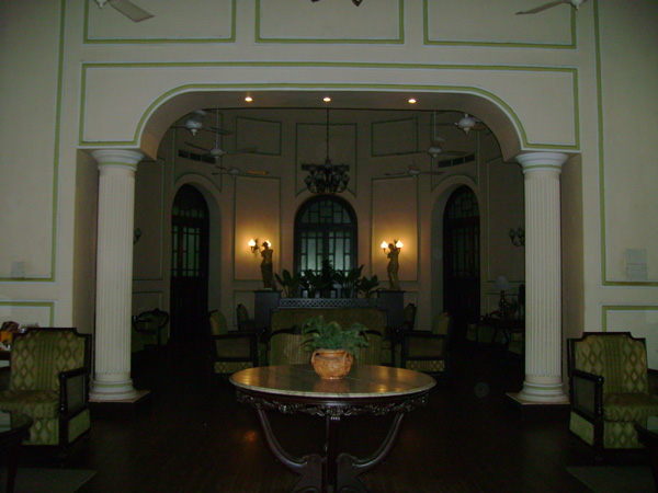 a very large room with columns, chandelier and potted plant