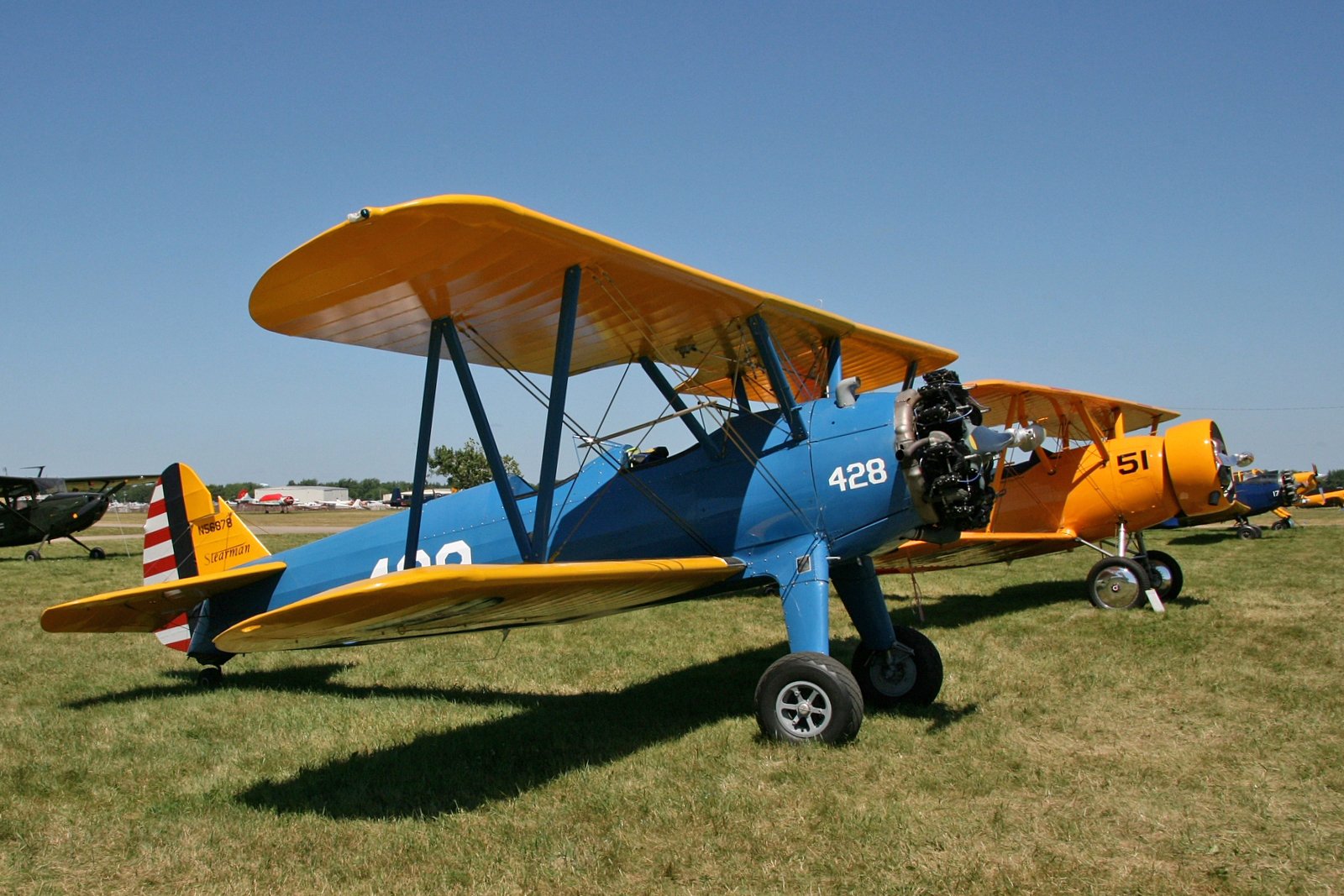 a yellow and blue airplane on display in the grass