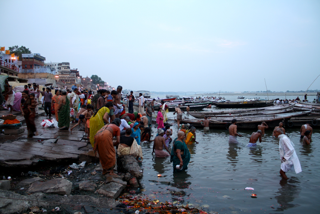 many people gather in the water near boats and a pier